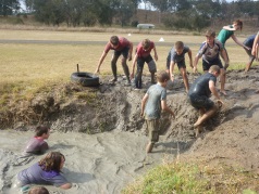 Students crawling out of mud on an obstacle course